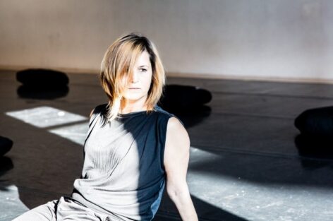 Amanda Loulaki sitting with the sun shinning on her. She is wearing a black top and has blonde hair cut in a bob. Photo by Scott Shaw.