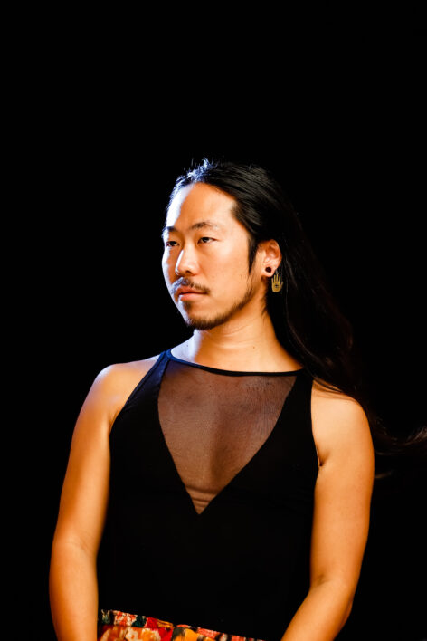 A Japanese person with shoulder-length hair, wearing a semi-transparent top and a hamsa earring. Photo by Kechi Chibueza.