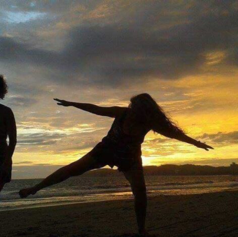 The silhouette a dancer on one leg with arms and other leg outstretched, in front of a sunset. Photo courtesy of the artist. 