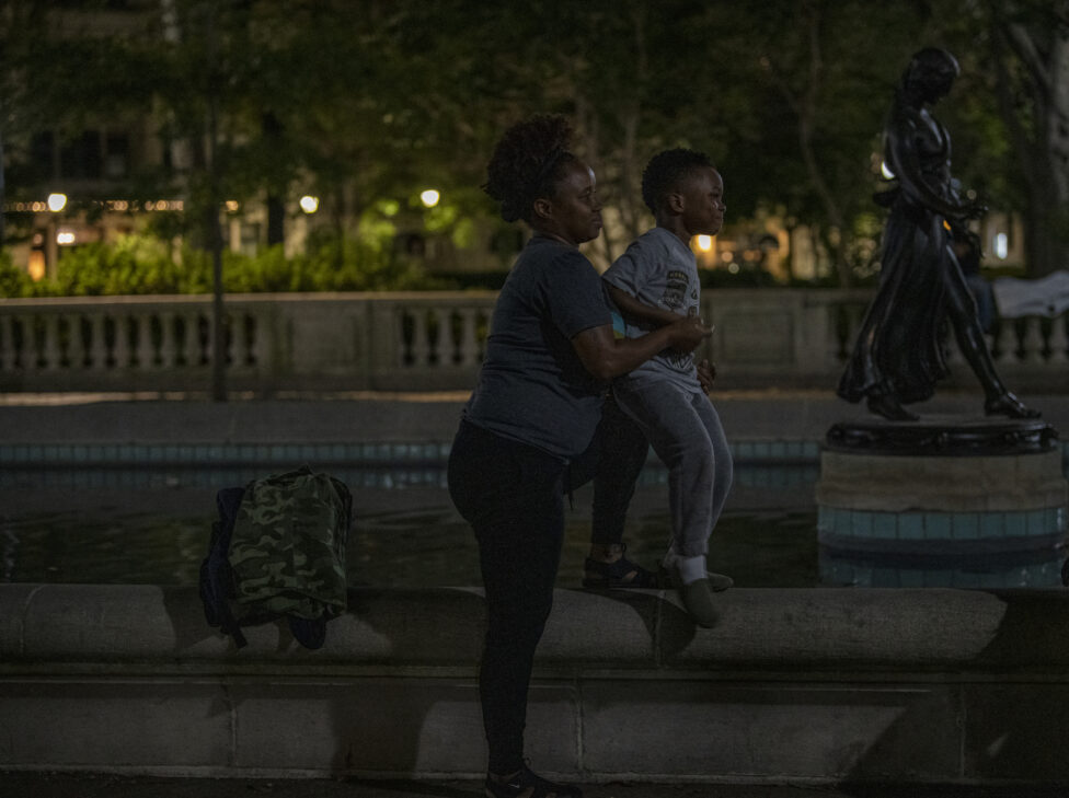 A woman lifting up a young boy up higher so he is able to see the band. They are smiling. 