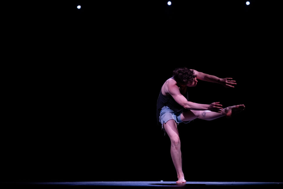 On a darkened stage, Leah dances under a spotlight.