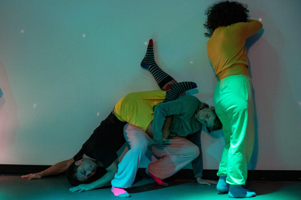 Three dancers, moving close to a wall. Image by Katie Barber. 