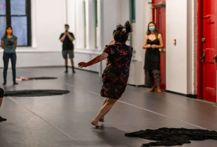 An Open Performance artist running in a black and red dress. Photo by Rachel Keane.
