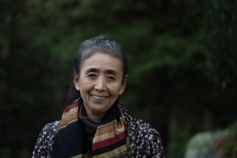Eiko smiles at the camera, she wears a striped scarf and patterned top. Photo by William Johnston.