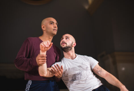 Paul Singh is catching Jack Blackmon as their shared weights collapses. Paul wears a long sleeve burgundy shirt, Jack is in a white t-shirt. Photo by David Gonsier.