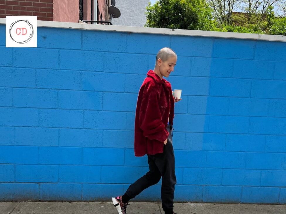 Roya walking in front of a blue wall. Days filled with long walks and friends during treatment, Bedstuy NYC